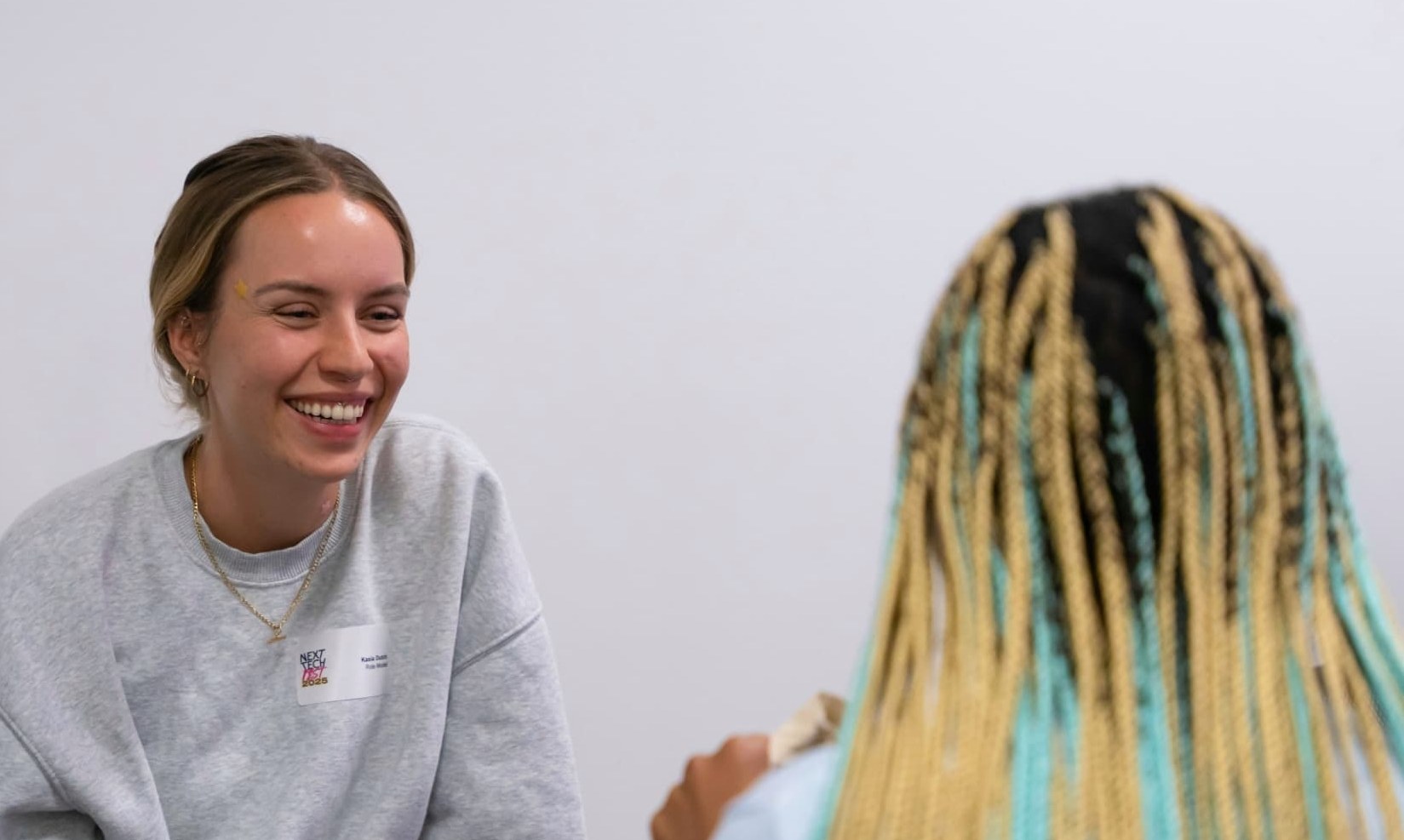 Kasia Dutch laughing in conversation at Next Tech Fest 2025, wearing a name badge reading 'Role Model'